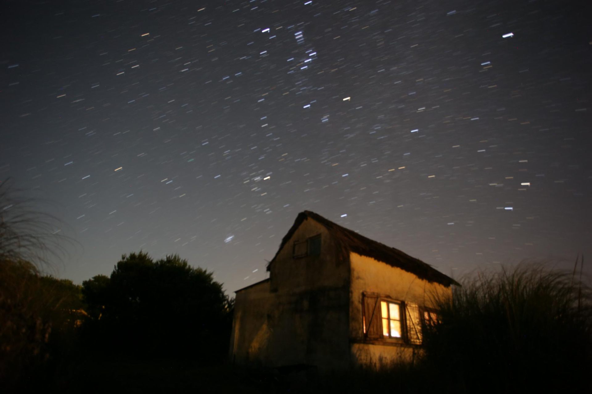 Casa bajo cielo estrellado, larga exposición