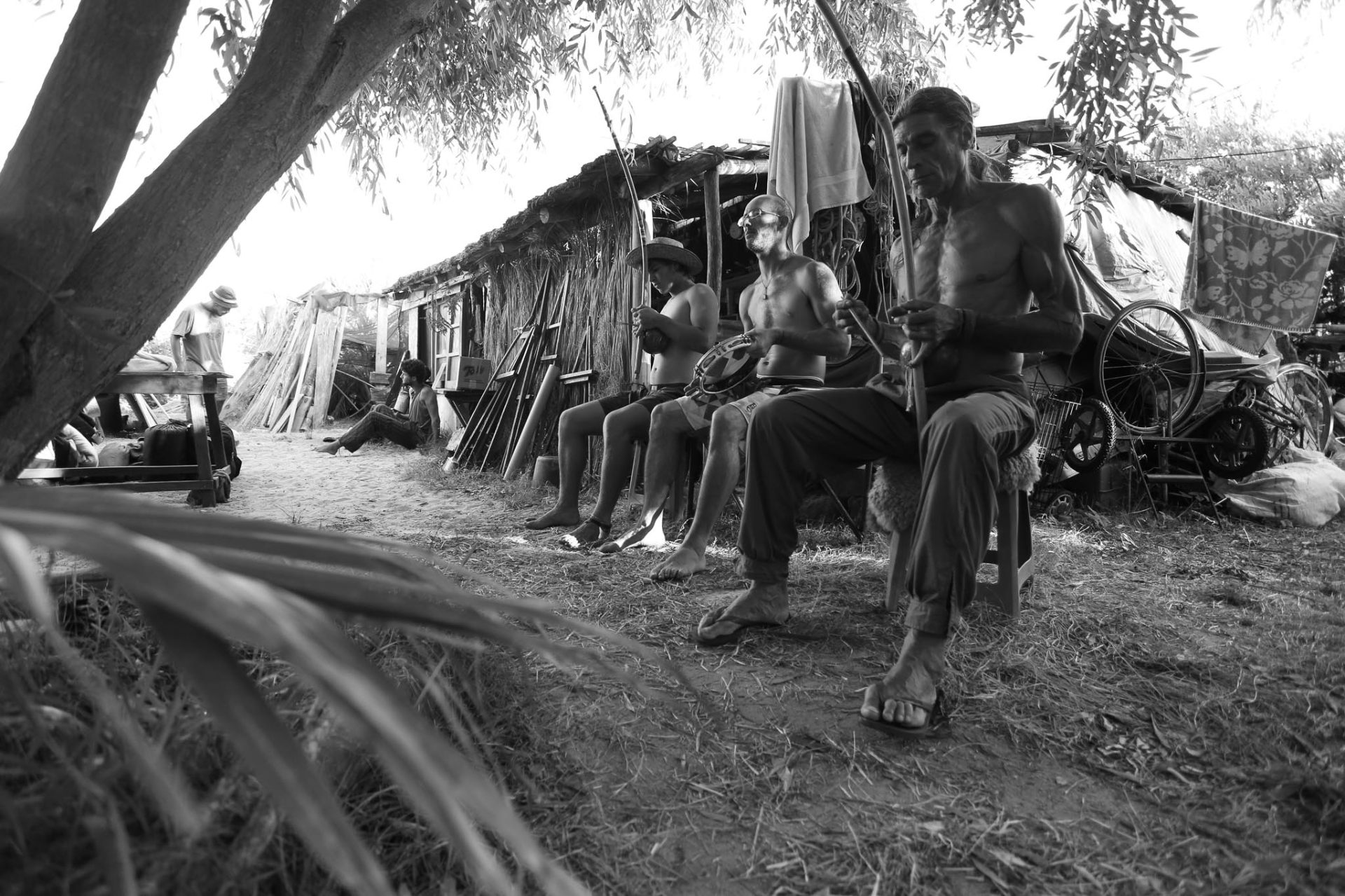 Tres músicos frente al rancho, berimbau y pandeiro