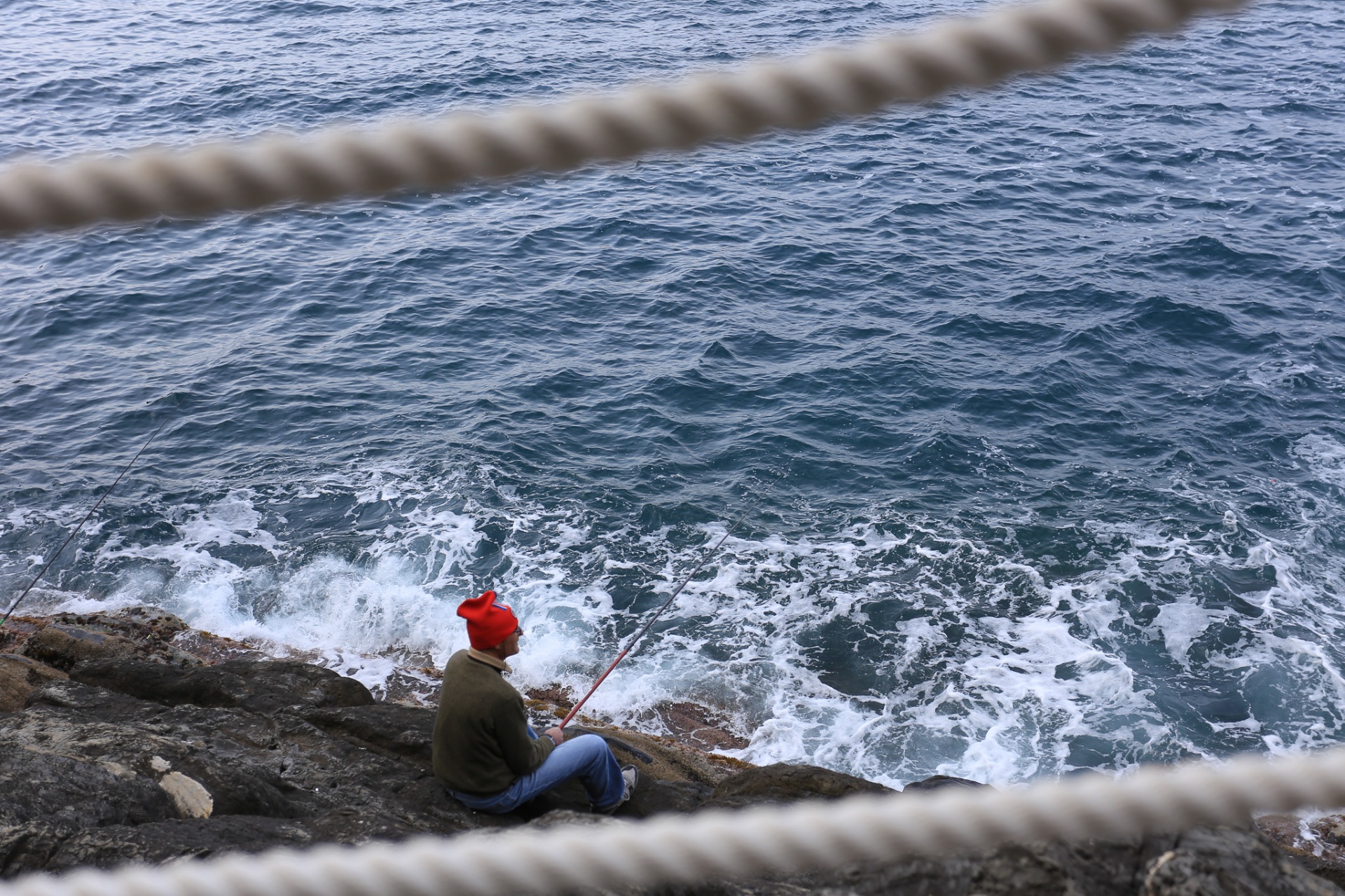 Pescador con gorro rojo entre cuerdas y olas