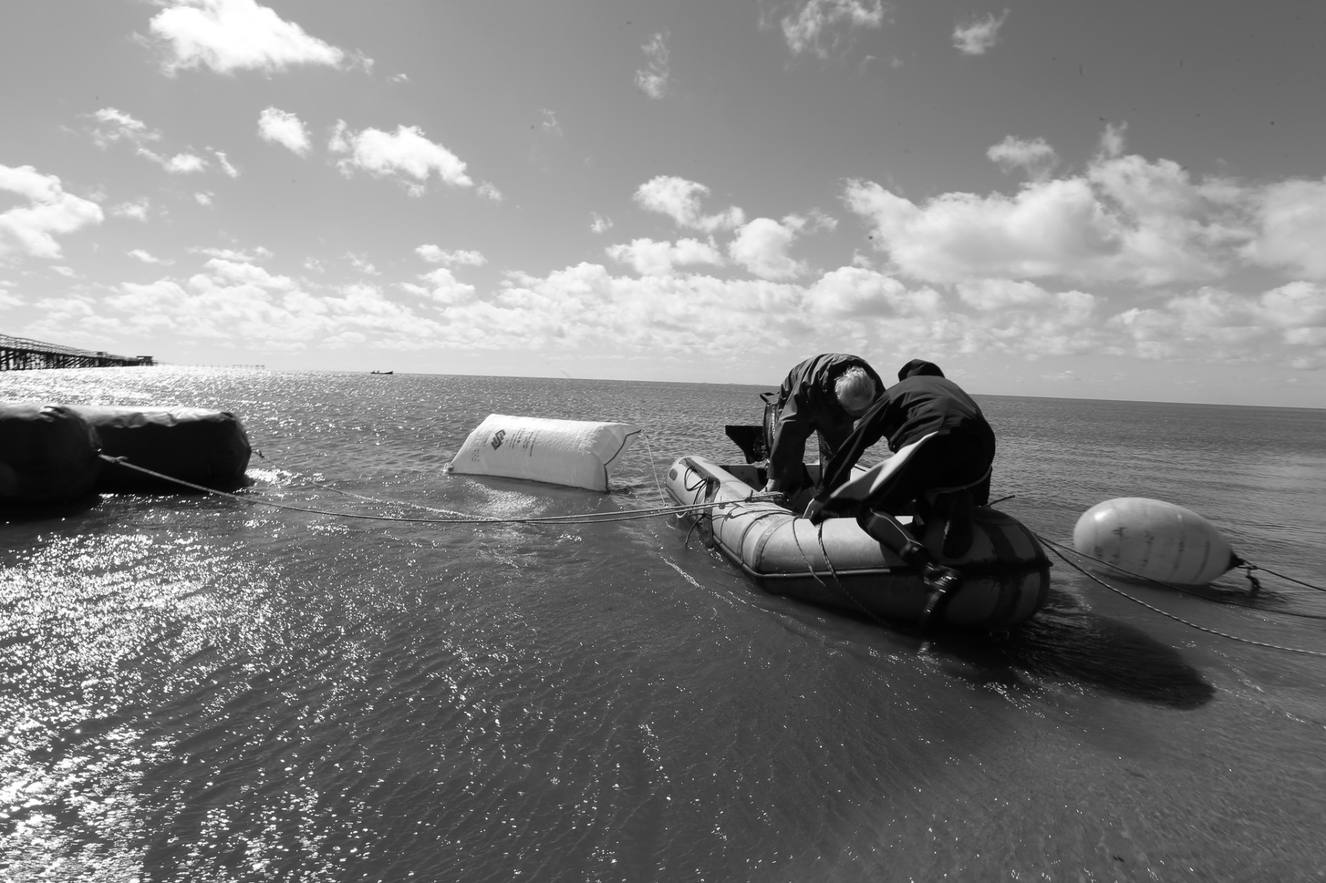 Dos hombres en bote inflable, faena en el agua