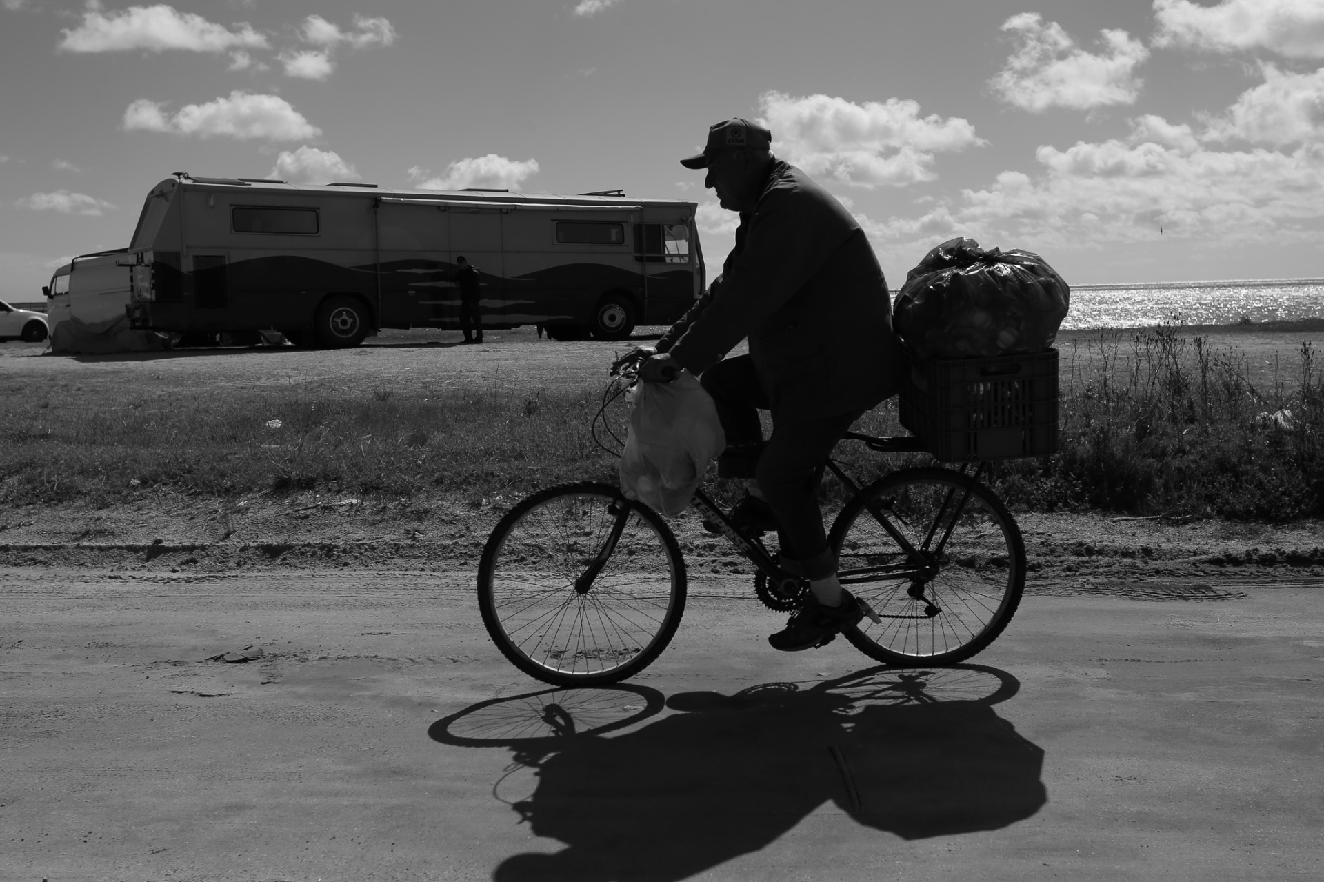 Hombre en bicicleta a contraluz, motorhome y mar