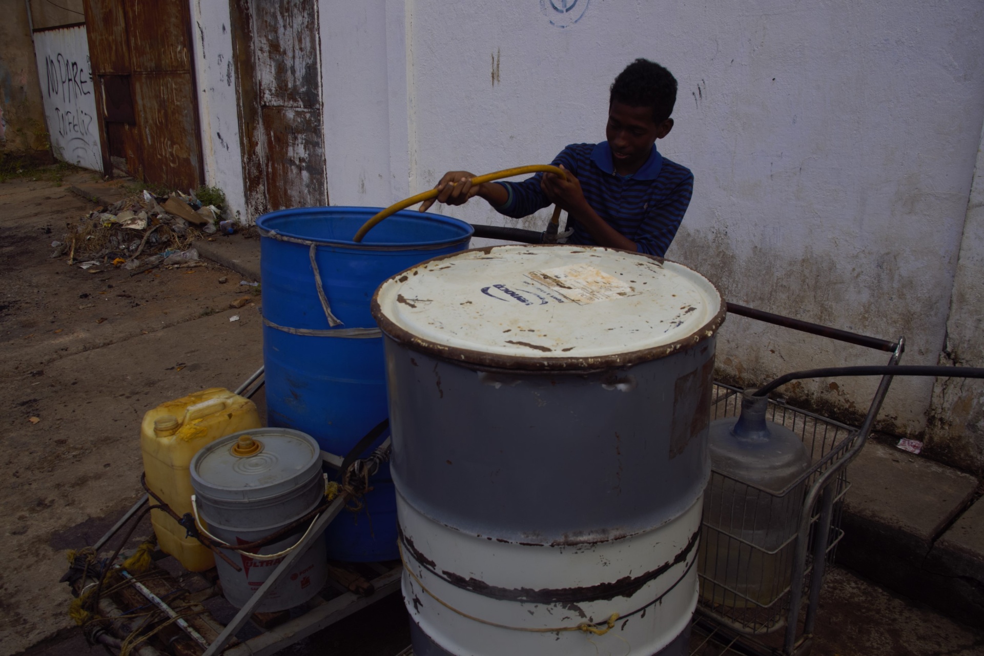 Joven llenando bidones de agua en la calle