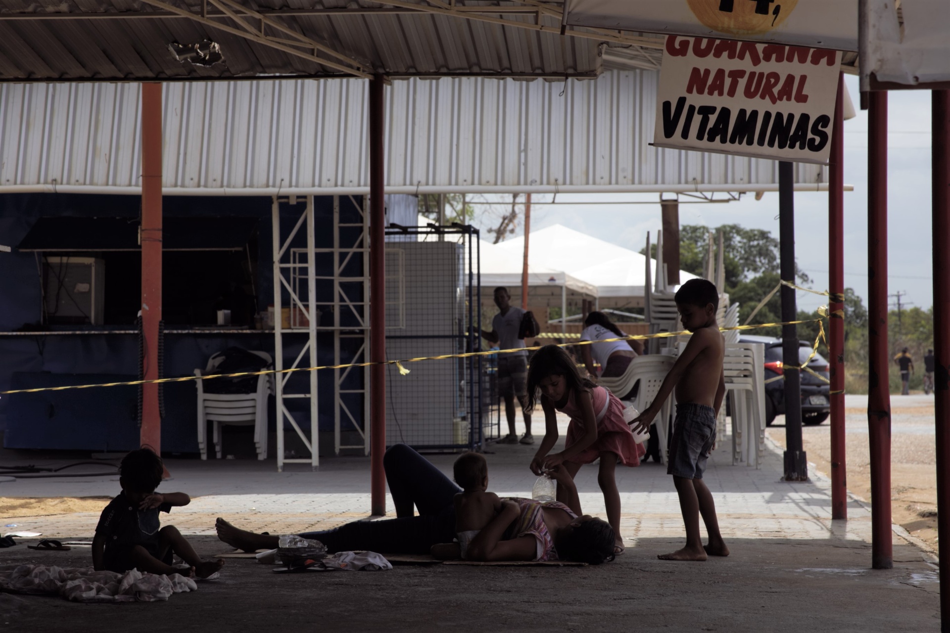Familia descansando bajo un puesto de comida en Boa Vista