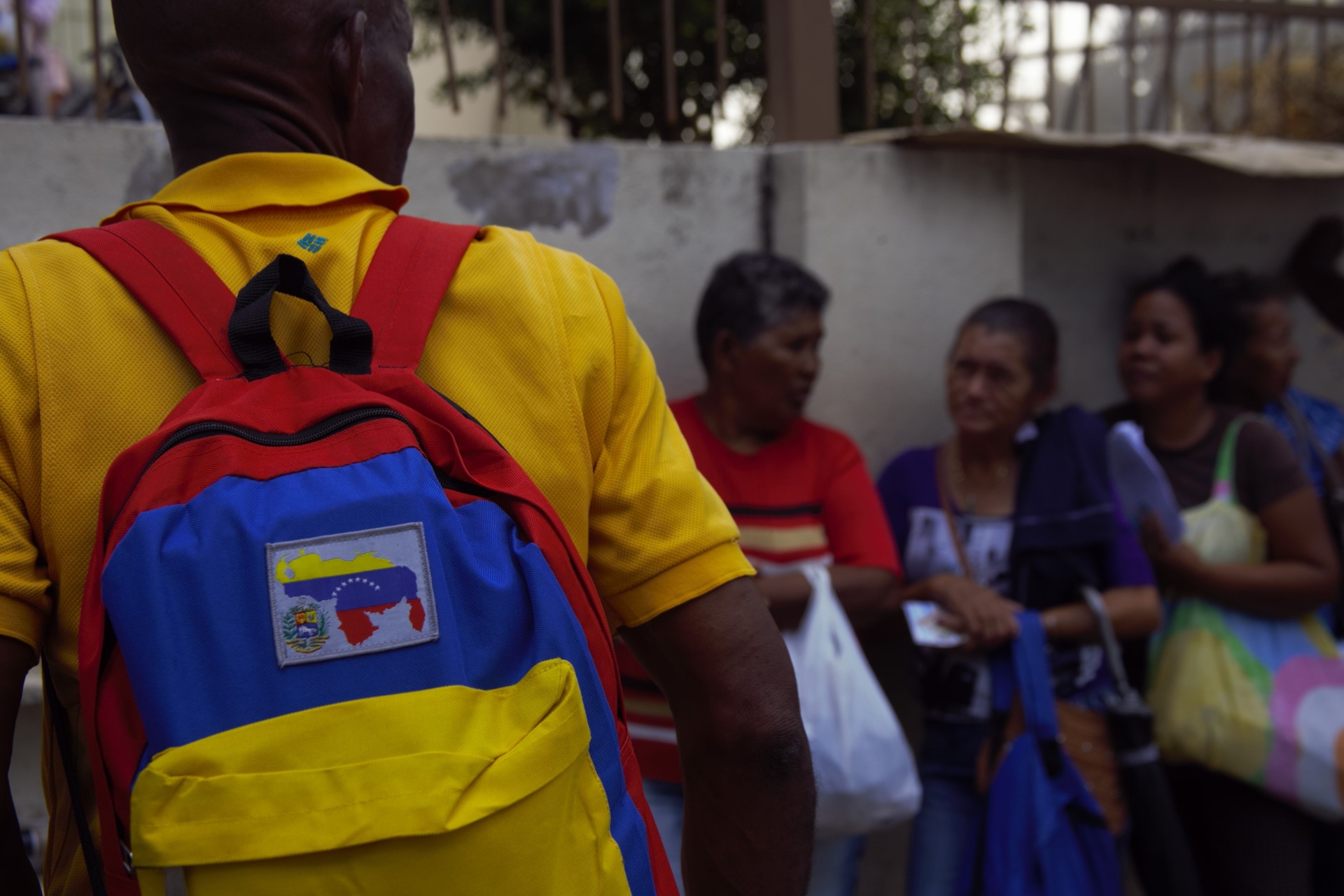 Hombre de espaldas con mochila con la bandera de Venezuela